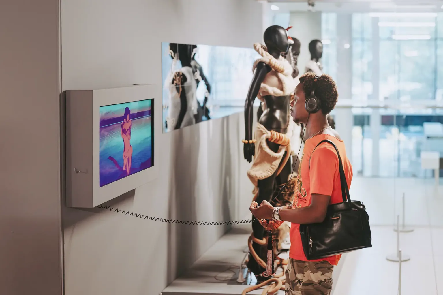 A man stands in front of a monitor, appearing engaged with the screen's content